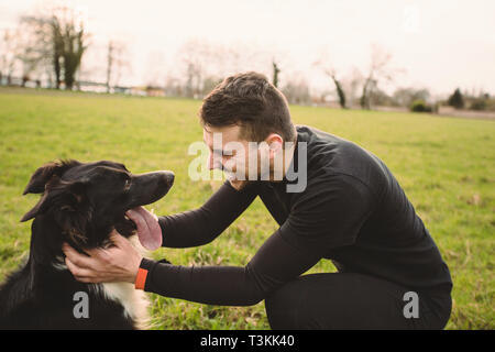 Cane e il suo proprietario divertirsi in un parco della città. Concetti di amicizia, animali domestici, stare insieme. Foto Stock