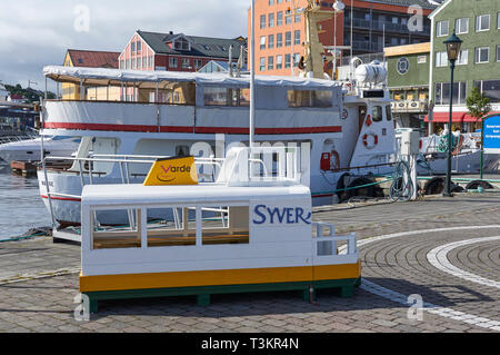 Una piccola barca Childs sedile sul Ferry Quay a Kristiansund, con una nave passeggeri legato sulla banchina su una giornata d'estate. La Norvegia. Foto Stock