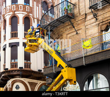 Tre uomini su una Houlotte HA 16 PX boom paranco la riparazione di un balcone in metallo a Siviglia, Spagna Foto Stock