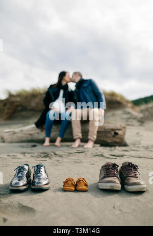 Famiglia di scarpe in sabbia con coppia baciare Foto Stock