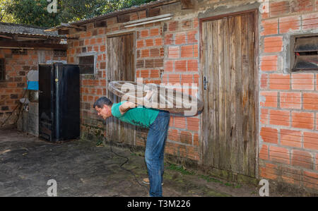 Un uomo che porta una ruota di legno sul suo retro. Foto Stock