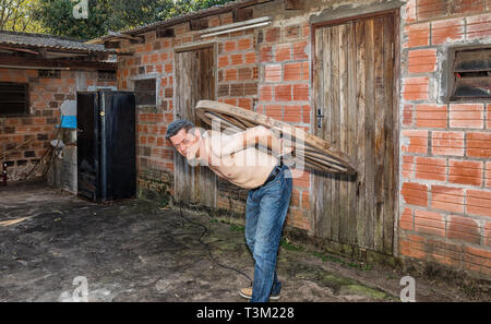 Un uomo che porta una ruota di legno sul suo retro. Foto Stock