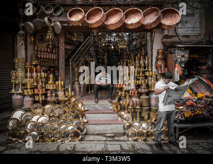 Gli uomini alla ricerca dopo un negozio a motivo chowk, vendita di rame battuto e ottone fuso, Kathmandu, Nepal Foto Stock