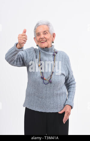 Donna anziana con il pollice in alto e sorriso su sfondo bianco Foto Stock