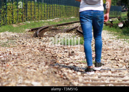 Giovane ragazzo bello camminare lungo la vecchia ferrovia, godendo i suoi dintorni sulla giornata di sole. Uomo di viaggiatori su ferrovia. Seguendo il vecchio percorso ferroviario. Foto Stock