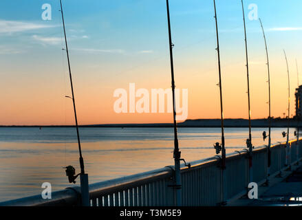 Poli di pesca rimangono inattivi come il sole tramonta a Florida punto pier, nov. 12, 2009, in Orange Beach, Alabama. Foto Stock