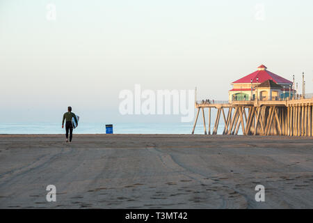 Surfer di uscire a prendere le onde sulla spiaggia nella luce del mattino Foto Stock