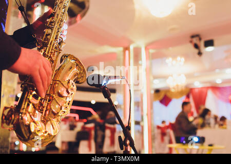 Golden sassofono nelle mani di un musicista in prossimità del microfono Foto Stock