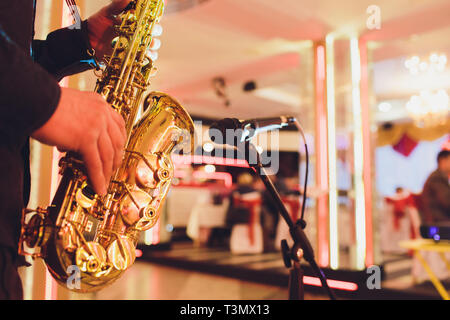 Golden sassofono nelle mani di un musicista in prossimità del microfono Foto Stock