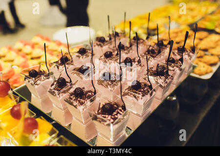 Il dessert con frutta, mousse, biscotti. Diversi tipi di paste dolci, piccole colorate torte dolci, macaron, e altri dessert al buffet dolce Foto Stock