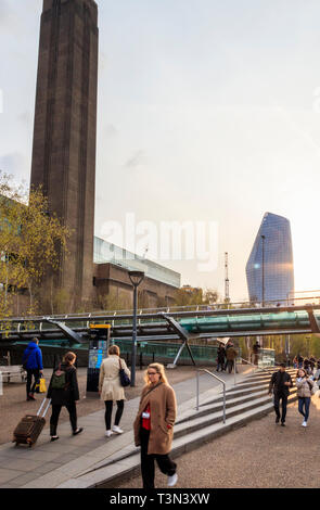 Turisti e pendolari a Bankside, Londra,UK, il Millennium Bridge e la Tate Modern art gallery, in background No.1 Blackfriars, aka "vaso". Foto Stock