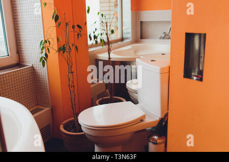 Nuovi servizi igienici vicino al grande finestra in bagno di colore arancione Foto Stock