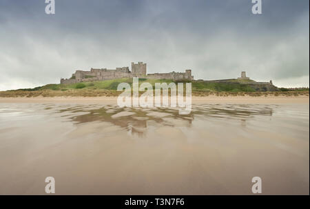 Il castello di Bamburgh, cova il cielo e la bella spiaggia vuota, Northumberland, Inghilterra, Regno Unito (Maggio 2017) Foto Stock