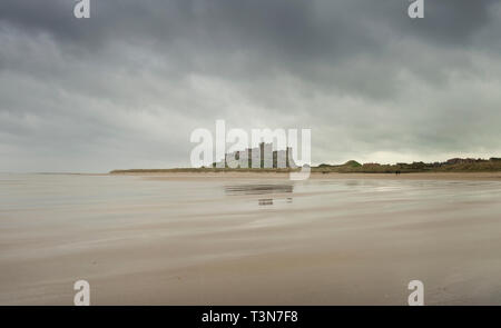 Il castello di Bamburgh, cova il cielo e la bella spiaggia vuota, Northumberland, Inghilterra, Regno Unito (Maggio 2017) Foto Stock