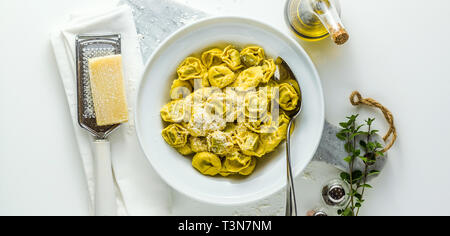 Banner della lastra di cotto italiano ravioli tortellini con il parmigiano a tavola. sano foodtable Mediterranea. la sana cucina mediterranea Foto Stock