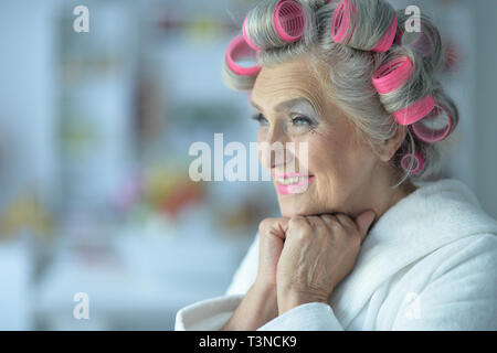 Close up ritratto di donna senior in accappatoio con bigodini Foto Stock