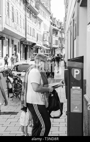 Strasburgo, Francia - Luglio 22, 2017: uomo di pagare per il parcheggio in cetral Strasburgo presso il parcheggio metro con la cattedrale di Notre Dame in background e dello shopping di Rue des Juifs in bianco e nero Foto Stock