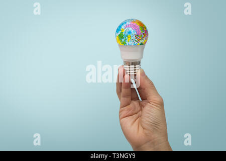 Mano tiene la lampadina a LED con il globo su sfondo blu. Foto Stock