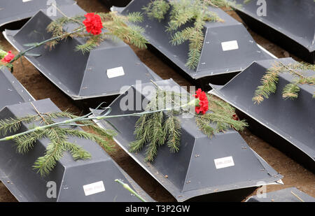 Stare Czarnowo, Polonia. Xi Apr, 2019. In una cerimonia in memoria del tedesco della Commissione delle tombe di guerra (Volksbund Deutsche Kriegsgräberfürsorge) per la sepoltura di 1500 Tedesco Guerra Mondiale II Guerra morti al war graves Stare Czarnowo (Neumark) 30 chilometri a sud est di Stettino in Polonia, i partecipanti hanno gettato fiori sulle bare simbolica. I morti sono esumato soldati e civili vittime di guerra dalla penisola di Hel, ex West Pomerania e Wartaland in Polonia attuale. Vittime della guerra si trovano tuttora e reburied vi. Credito: Bernd Wüstneck/dpa/Alamy Live News Foto Stock