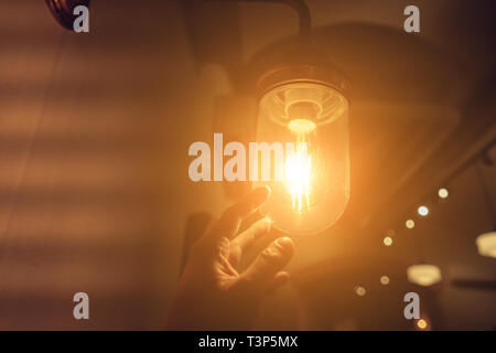 La mano di raggiungere per un vintage lampadina. Foto Stock