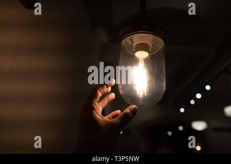 La mano di raggiungere per un vintage lampadina. Foto Stock