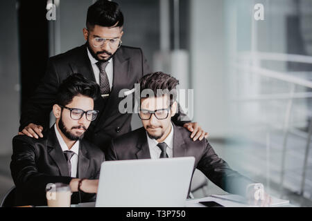 Ritratto di tre collaboratori a discutere di business plan in ufficio Foto Stock