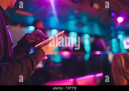 Evento di controllo di sintonizzazione audio dal tablet sullo sfondo di un karaoke bar. Foto Stock