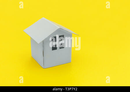 Semplicemente dal design minimale con bianco in miniatura toy casa isolata su giallo colorato moderno e alla moda fashion background. Ipoteca assicurazione immobiliare sogno