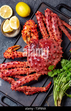 Red king crab su sfondo grigio. Granchio reale, limone e coriandolo, vista dall'alto Foto Stock