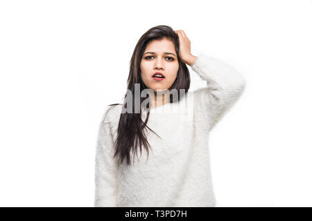 Closeup ritratto di confuso giovane donna indiana ponendo la mano sulla testa, palm sulla faccia gesto in duh momento isolato su sfondo bianco. Foto Stock