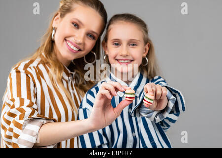 Gioiosa bella signore presentando tiny hamburger nelle loro mani Foto Stock