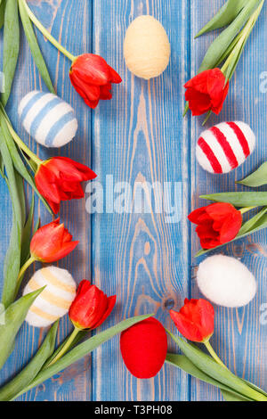 Freschi tulipani rossi e uova di Pasqua avvolto stringa di lana su vecchie schede, festosa concetto di decorazione, copia spazio per il testo Foto Stock