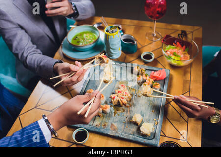 Una cena in famiglia tenendo le bacchette sul set di sushi. Appartamento laico, vista dall'alto. Foto Stock