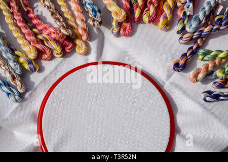 Telaio per ricamo con tela colorata e fili di cucitura. Foto Stock