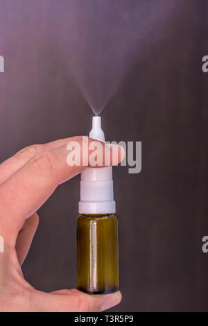 L'uomo spinge sulla testa di spruzzatura di un Nasensprays, in modo che il getto è creato Foto Stock