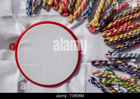 Telaio per ricamo con tela colorata e fili di cucitura. Foto Stock