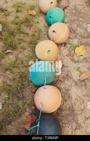 Divertente volto realizzato a mano in una boa arancione in cima a una roccia sulla spiaggia di una scogliera. faccia con gli occhi e la bocca e un bianco il sacchetto in plastica rendendo Foto Stock