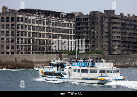 Giappone: Prefettura di Nagasaki. Imbarcazione turistica prossimi a fianco della isola abbandonata di Hashima che era noto per il suo sottomarino miniere di carbone, una volta che la maggior parte d Foto Stock