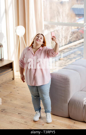 Vista dall'alto di una gioiosa plump donna di scattare le foto Foto Stock