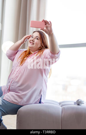 Bella donna positiva tenendo una bella selfie Foto Stock