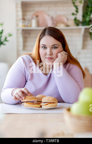 Piacevole guardando bene donna seduta in cucina Foto Stock