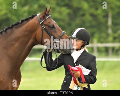 Una giovane donna di coccole il suo cavallo dopo aver vinto un premio. Foto Stock