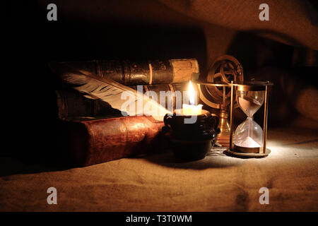 Vintage vita ancora con clessidra vicino alla candela di illuminazione e libri Foto Stock