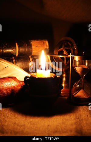 Vintage vita ancora con clessidra vicino alla candela di illuminazione e libri Foto Stock