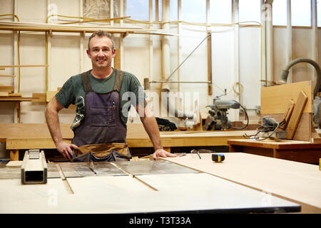 Carpenter sorridente in officina Foto Stock