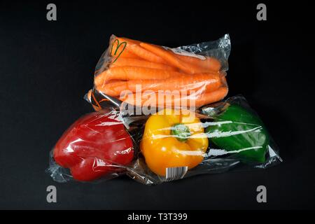 Rosso, giallo e i peperoni verdi (Capsicum annuum) e carota (Daucus carota) dal supermercato avvolti in una pellicola termocontrattile in plastica, verdure in plastica Foto Stock