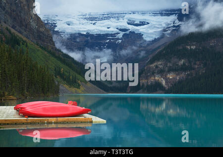 Canoe sul dock in legno oltre ancora lago remoto Foto Stock