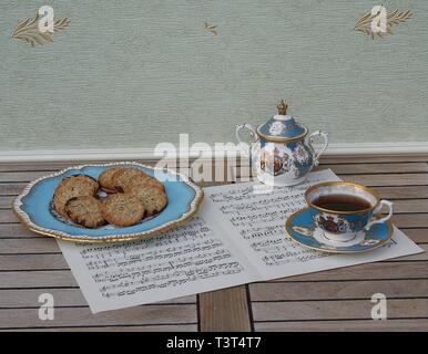 Inglese tazzina con piattino, Sugar Bowl una torta e una piastra con i cookie, raffinato osso di cina in porcellana, su un foglio di musica Foto Stock