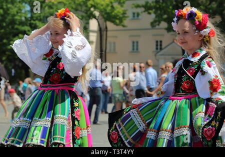 Due sorella vestite nei tradizionali costumi folcloristici dalla regione di Lowicz, con corona sul teste, rappresentano per la foto sulla piazza, Corpus Domini vacanza, le persone. Foto Stock