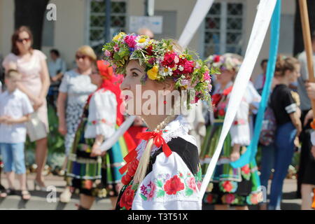 Ritratto di giovane e bella donna vestita nei tradizionali costumi folk dalla regione di Lowicz in Polonia, altre persone durante la processione del Corpus Domini. Foto Stock